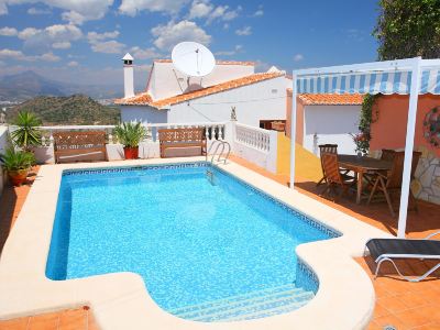 a large swimming pool is surrounded by a white house with a blue tile roof at Joli Joli Photo