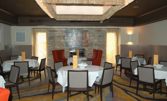 a restaurant with a brick wall and fireplace , featuring a dining table with chairs and a large painting on the wall at Best Western Plus Chelmsford Inn