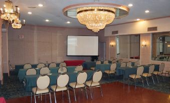 a large conference room with blue tables , white chairs , and a chandelier hanging from the ceiling at Best Western Plus Wilkes Barre Center City