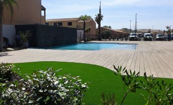a modern outdoor pool area with wooden decking , green artificial grass , and buildings in the background at Balnea