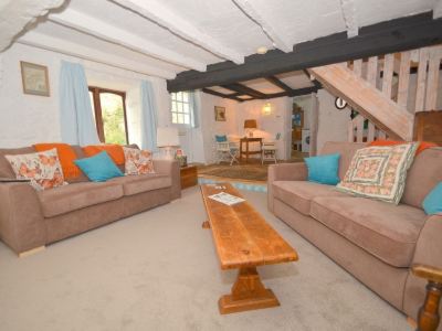 a cozy living room with a brown couch and chairs , a wooden coffee table , and a dining table at Kim