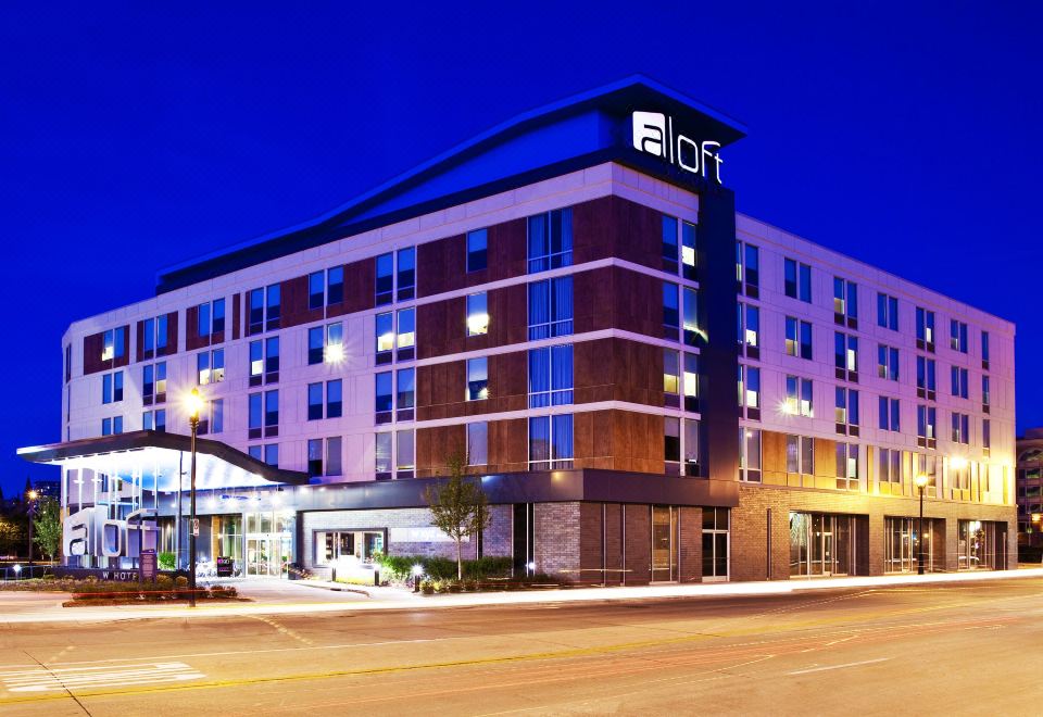 an aloft hotel at night , with its name prominently displayed on the front of the building at Aloft Milwaukee Downtown