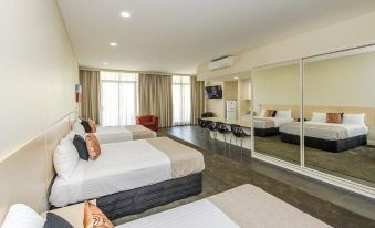 a modern hotel room with multiple beds , white bedding , and a large mirror reflecting the room 's design at Belconnen Way Hotel & Serviced Apartments