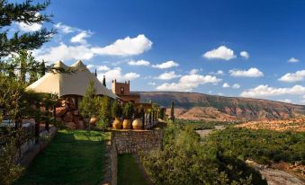 a beautiful mountain landscape with a villa surrounded by trees , and a clear blue sky at Kasbah Tamadot
