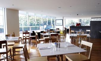 a large dining room with wooden tables and chairs arranged for a group of people at Quest Brighton on the Bay