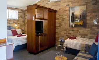 a hotel room with two beds , a couch , and a television mounted on the wall at Rest Point Motor Inn