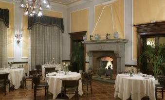 a large , elegant dining room with white tablecloths on the tables and a fireplace in the background at Sina Brufani