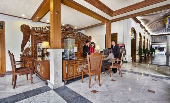 a man and a woman are sitting at a desk in a hotel lobby , engaged in conversation at Kusuma Sahid Prince Hotel Solo