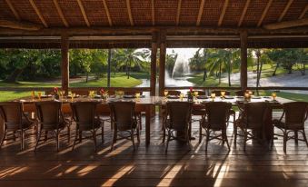 a long wooden table with chairs is set up in a room with a view of water at Tivoli Ecoresort Praia do Forte