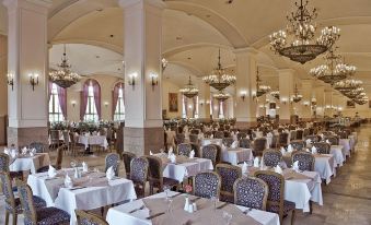 a large , ornate dining room filled with tables and chairs , all set for a formal event at Kremlin Palace