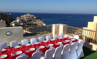 a long dining table set up for a party , with a view of the ocean in the background at Alexandra Hotel