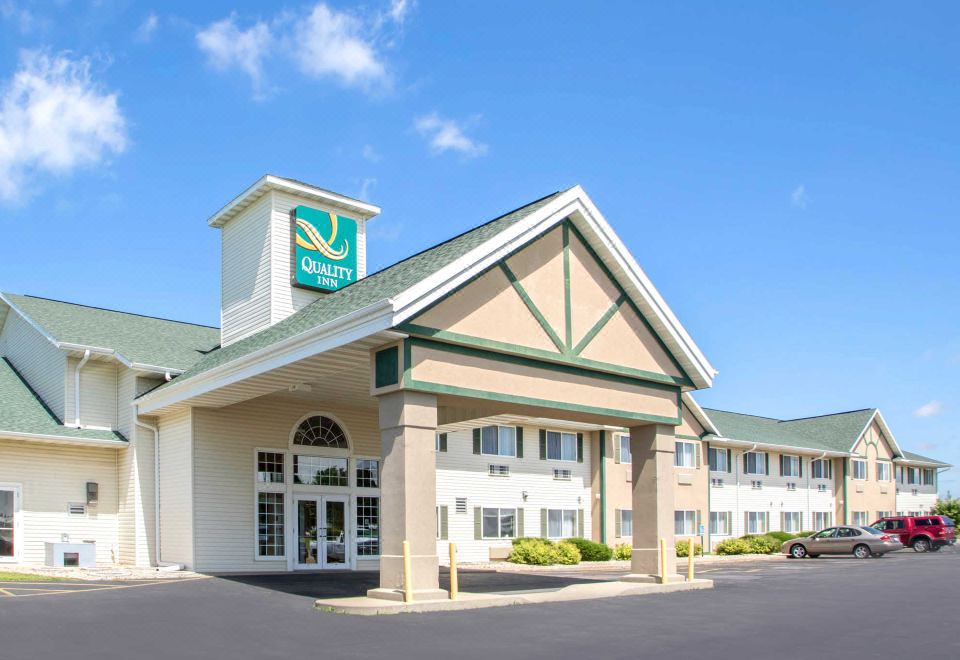 a holiday inn express hotel with its distinctive green and white design , surrounded by clear blue skies and tarmac at Quality Inn