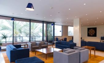 a modern living room with blue couches , chairs , and a coffee table , along with a dining table and chairs at Monte Mar Palace Hotel