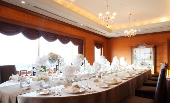 a long dining table set for a formal event , adorned with white flowers and candles at Hotel Metropolitan Nagano
