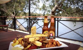 a plate of food with meat and cheese , two bottles of beer , and a view of the water at Ravenswood Hotel