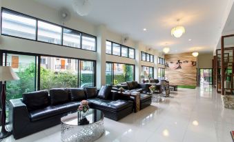 a spacious living room with black leather couches , chairs , and a dining table in the background at Soho Boutique Hotel