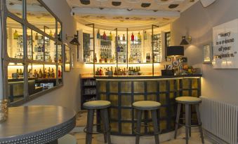 a modern bar with a round counter , three stools , and various bottles of alcohol on display at The Painswick