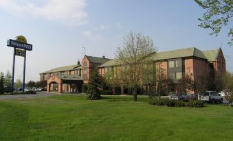 a large building with a green roof and many windows is surrounded by trees and grass at Hotel WelcomInns