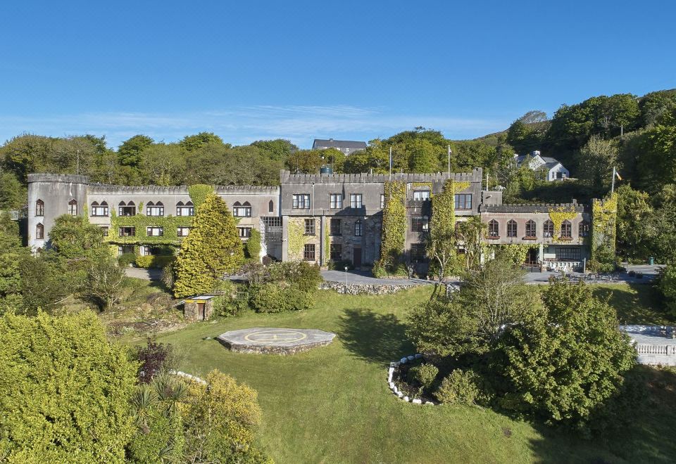 an aerial view of a large , modern building surrounded by greenery and a garden , with the sky visible in the background at Abbeyglen Castle Hotel