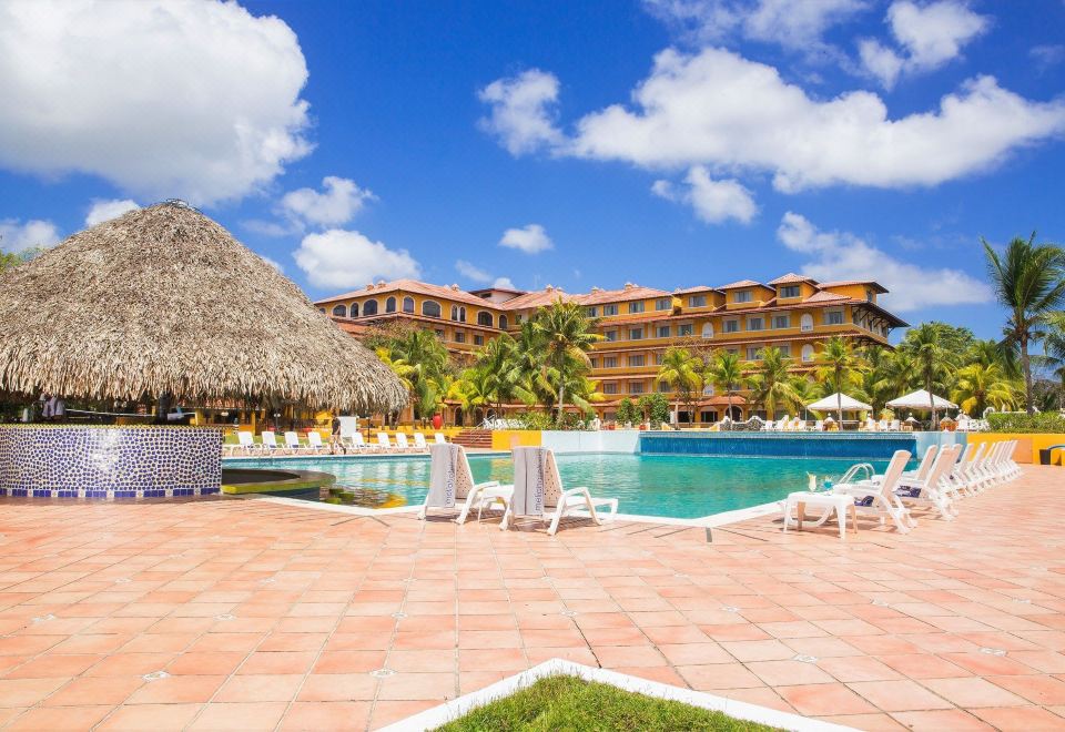 a resort with a large pool surrounded by lounge chairs and umbrellas , as well as a building in the background at Melia Panama Canal