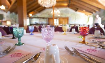 a table is set with a white tablecloth , pink napkins , and wine glasses in front of a chandelier at Madonna Inn