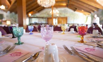 a dining table with multiple wine glasses and plates set for a formal dinner , surrounded by elegant decorations at Madonna Inn