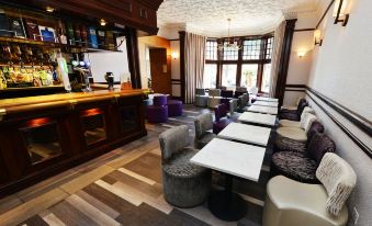 a modern bar area with several tables and chairs , creating a comfortable and inviting atmosphere at Glynhill Hotel & Spa Near Glasgow Airport