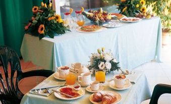 a table is set with plates of food , cups of orange juice , and a flower arrangement at Hotel la Luna