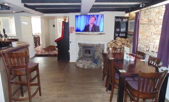 a room with a large screen , wooden table and chairs , and a fireplace is shown at The Kings Head