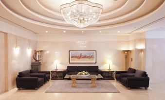 a well - lit living room with multiple couches , chairs , and a large chandelier hanging from the ceiling at Hotel Resol Gifu