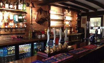 a bar with a wooden bar top , several beer taps , and a variety of bottles on display at The Bowl Inn