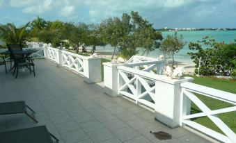 a sunny day at the beach with a white fence and chairs , overlooking the water at Cottage Cut Villas