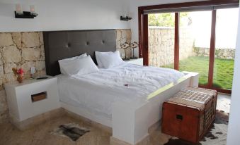 a white bed with a headboard and footboard is in a bedroom next to a window at La Ardileña