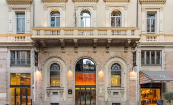 a brick building with an arched entrance and a large window , located on a city street at Room Mate Giulia