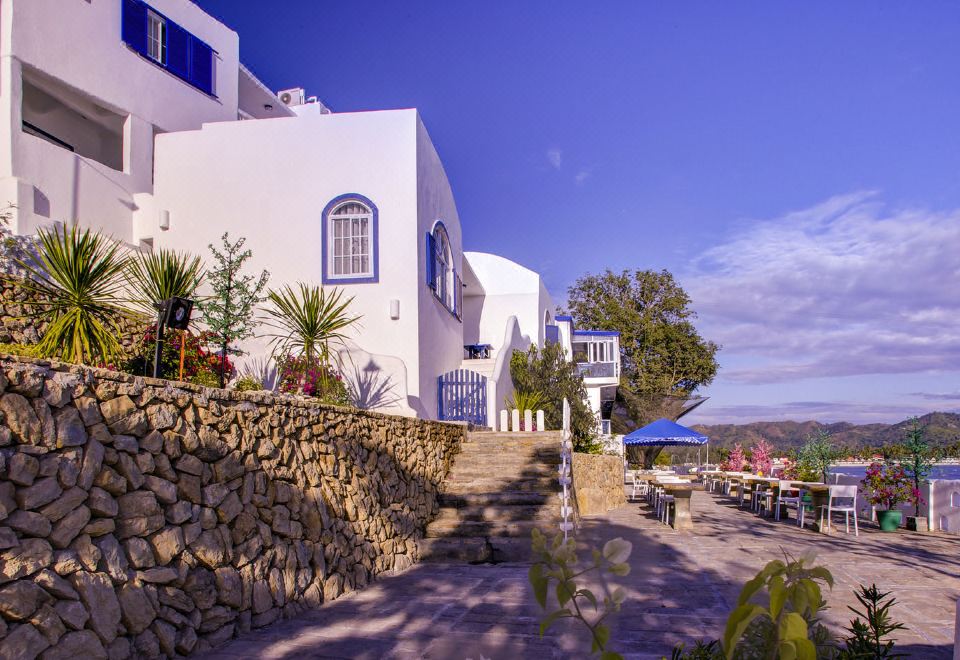 a white building with blue windows and a stone staircase leading to a patio area at Vitalis Villas