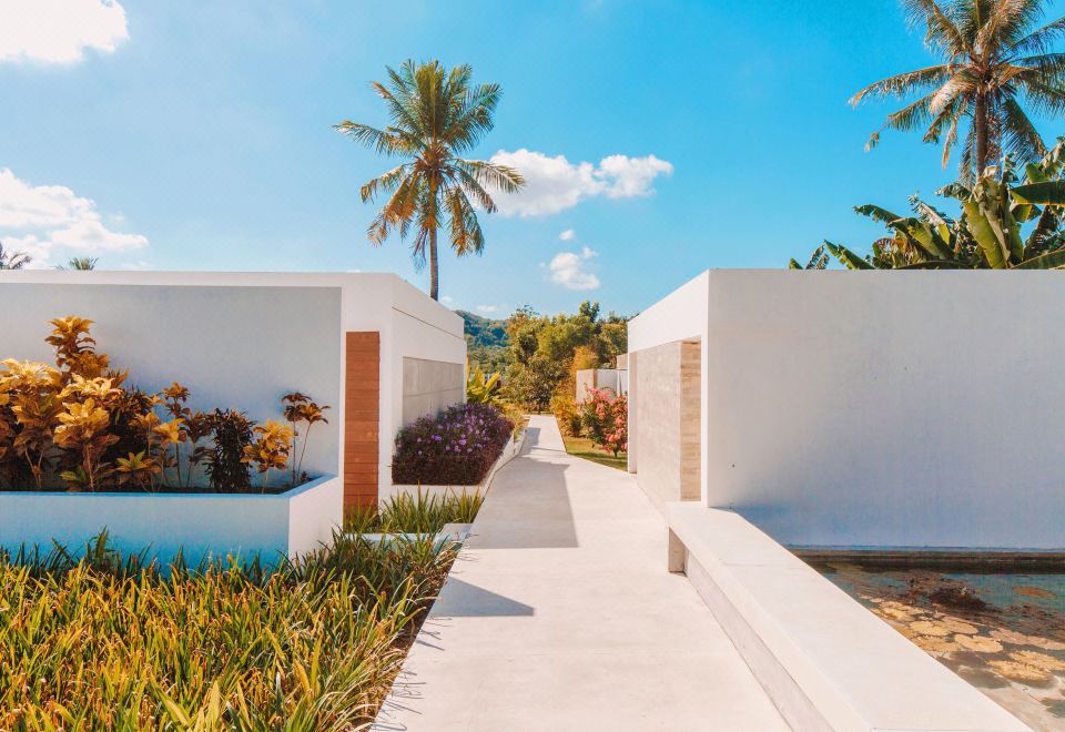 a modern , white building with a red brick exterior and palm trees in the background at Origin Lombok