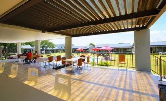 a wooden patio with tables , chairs , and umbrellas , providing a pleasant outdoor dining area for guests at Travelodge Kasane
