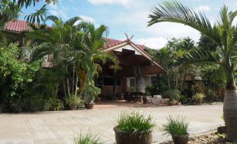 a beautiful wooden house surrounded by lush greenery , with palm trees and other plants in the yard at Phutawan Kan Resort