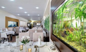 a large dining room with tables and chairs , and a fish tank in the background at Hotel Dixon so Vstupom do bazéna a vírivky Zdarma - Free Entrance to Pool and Jacuzzi Included