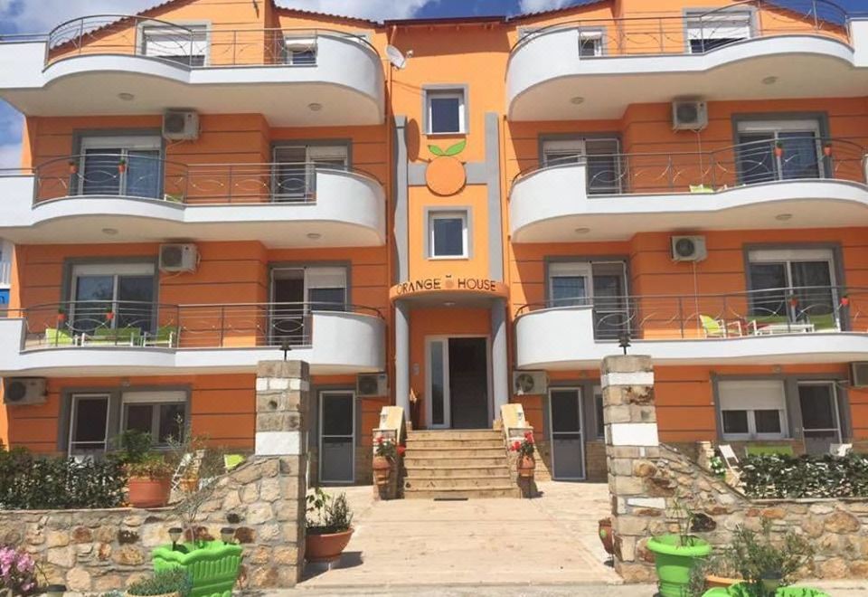 a large orange and white apartment building with multiple balconies and plants in front of it at Orange House