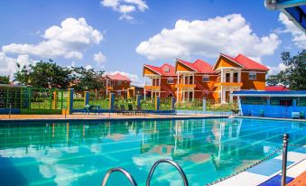 a large outdoor swimming pool surrounded by a fence , with multiple houses in the background at Country Inn Masindi