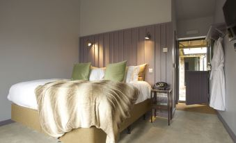 a large bed with a gold and beige comforter is in a room with gray walls at The Welldiggers Arms