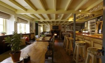 a large , well - lit room with wooden tables and chairs , a bar area , and a fireplace at The Welldiggers Arms