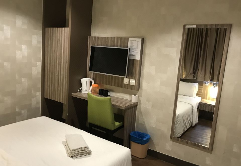 a hotel room with a bed , desk , and tv , as well as a chair and a mirror at Victory Hotel