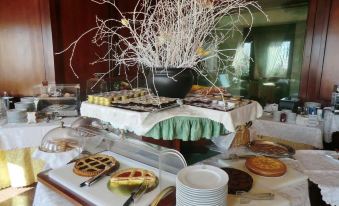 a table is set with a variety of pastries , desserts , and drinks , including cakes , pies , and beverages at Hotel Bellavista