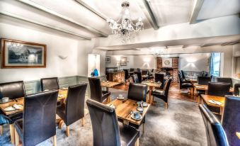 a large dining room with black leather chairs and tables , a chandelier hanging from the ceiling at Seacrest Hotel