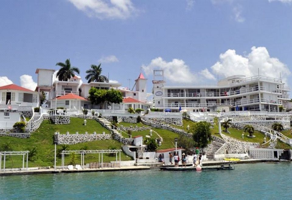 a white building situated on the side of a body of water , with a boat docked nearby at Hotel Laguna Bacalar