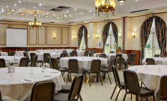 a large , well - lit banquet hall filled with tables and chairs , ready for a formal event at Quorn Country Hotel