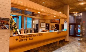 a modern reception area with an orange counter , black signs , and a sign pointing to the underground digital shop bar at Desert Cave Hotel