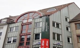 a building with a red sign for the hotel in german , and a sign on the side of the building at Avenue Hotel